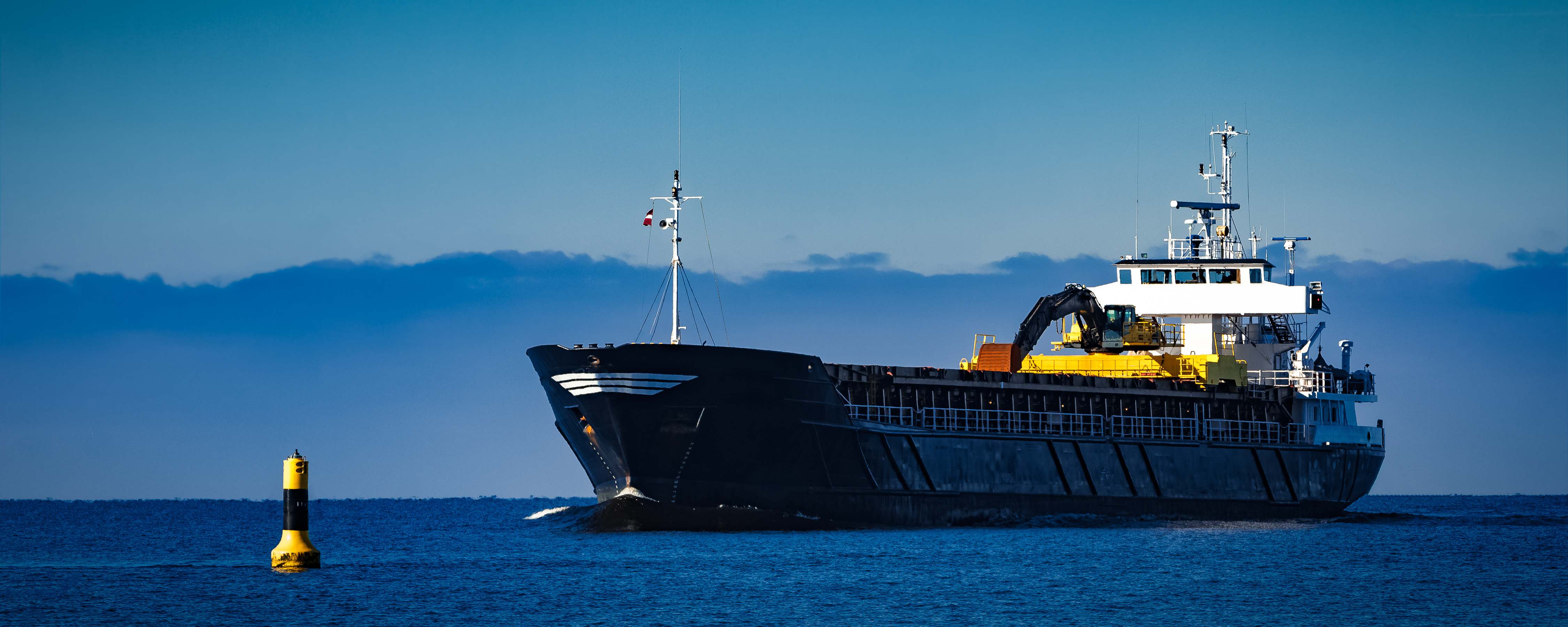 Black cargo ship with long reach excavator moving by baltic sea Black cargo ship with long reach excavator moving by baltic sea